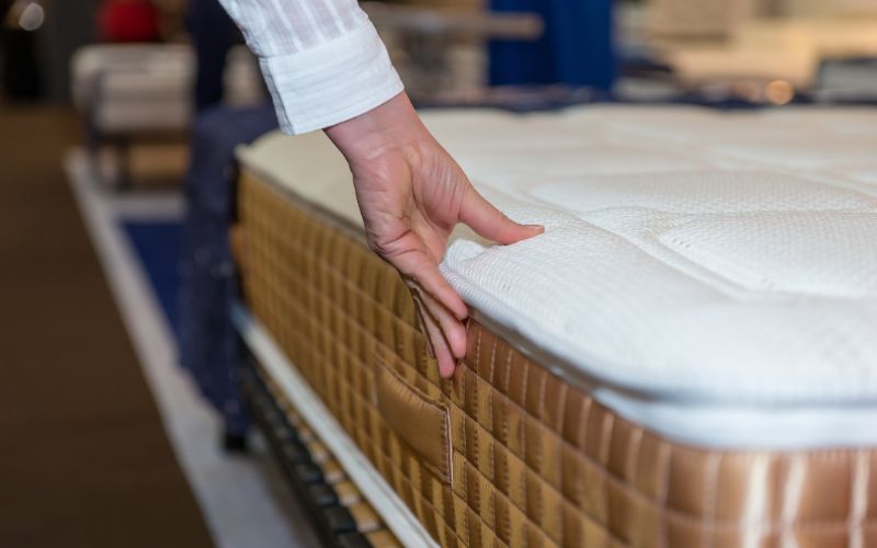 mattress-for-sale-close-up-of-female-hand-touching-and-testing-mattress-in-a-store-min